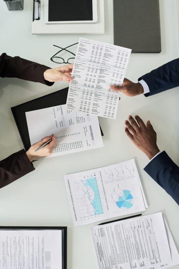 Business Colleagues Examining Financial Documents At Meeting Business Colleagues Examining Financial Documents At Meeting